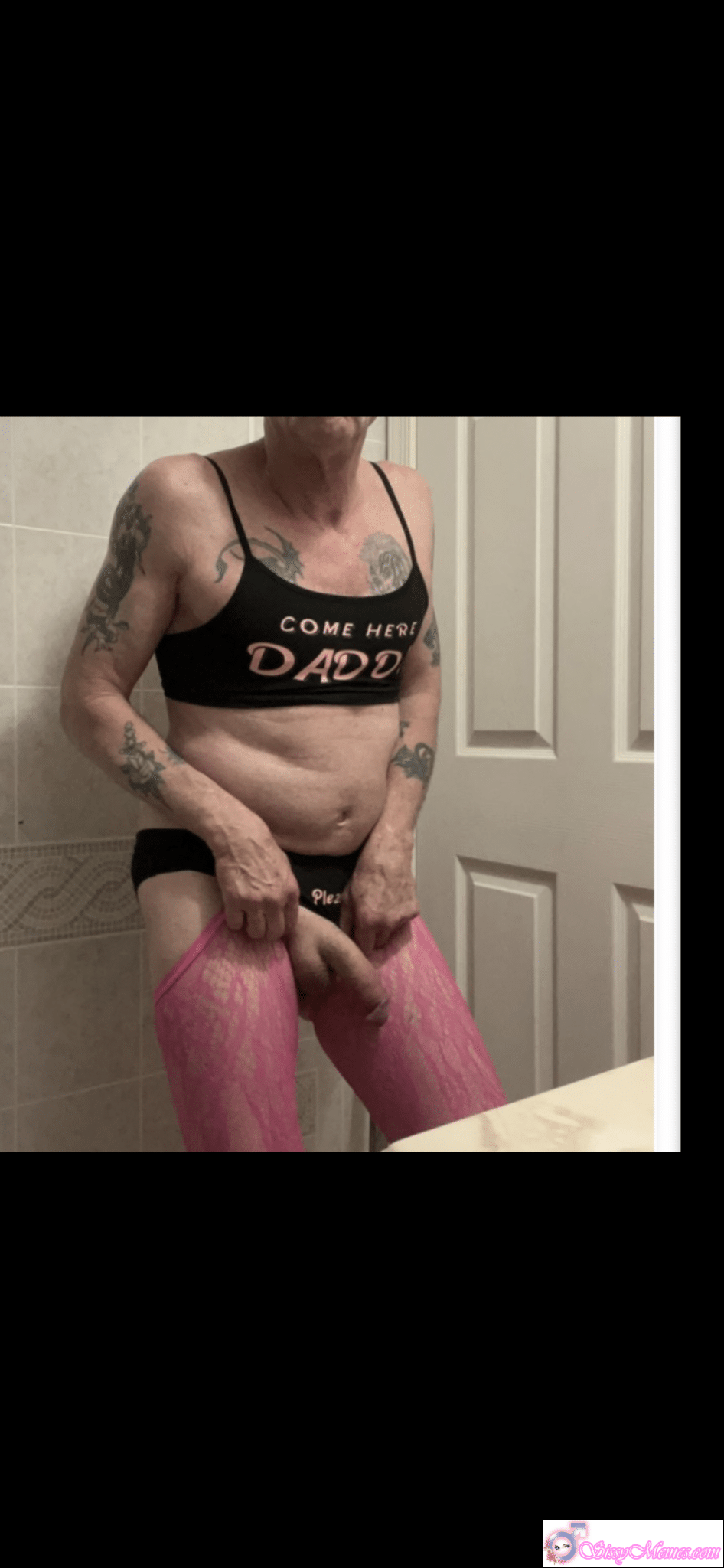 Sissygasm Porn Blowjob sissy caption: Feminized man in bathroom, wearing black sports bra with 'COME HERE DADDY' and pink lace stockings, masturbating with thong pulled down. Bald Sissy Cock Tease in Pink Lace